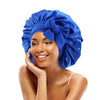 A woman wearing a royal blue satin sleeping cap with an adjustable tie band.