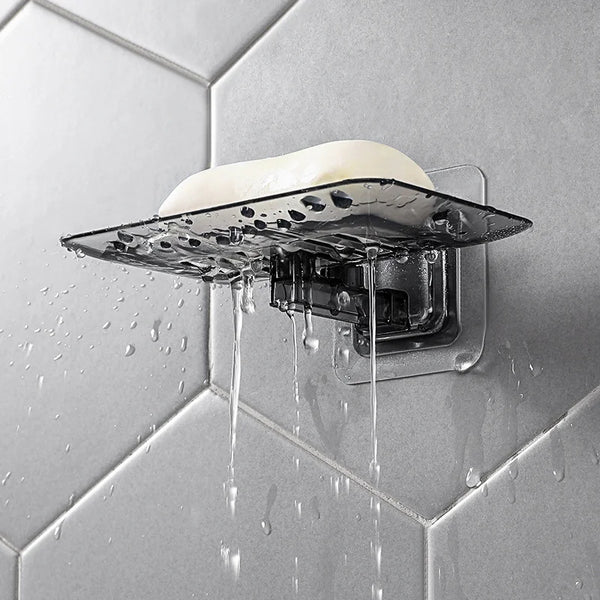 A wall-mounted double layer soap rack dripping water onto a tiled surface.