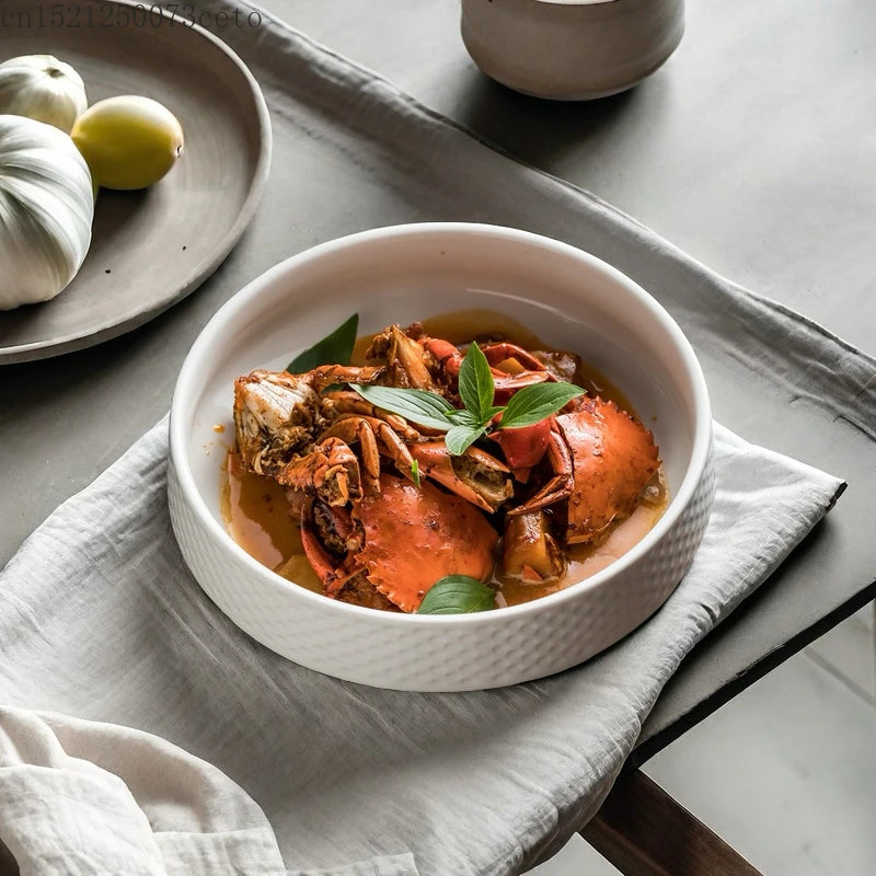 A white ceramic bowl filled with a savory orange-colored soup featuring pieces of cooked meat and garnished with fresh green 