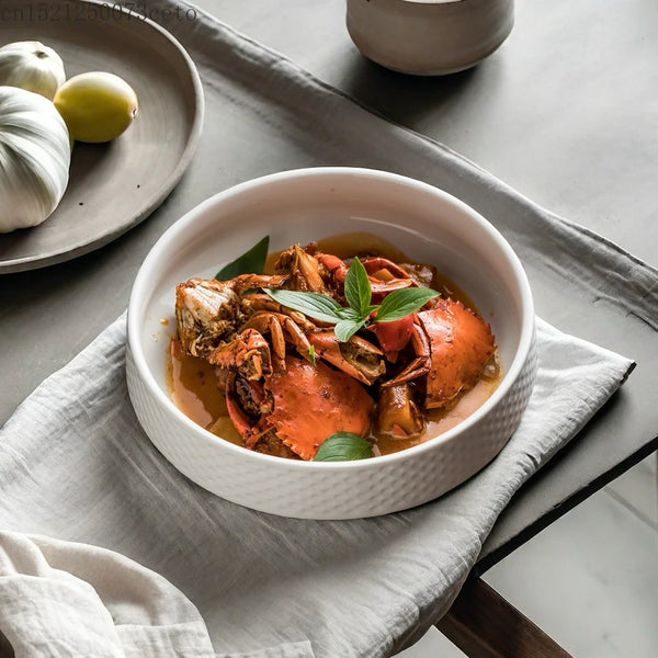 A white ceramic bowl filled with a savory orange-colored soup featuring pieces of cooked meat and garnished with fresh green 
