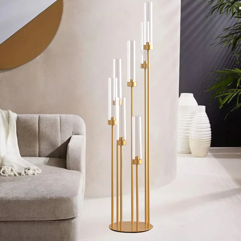 Un juego de candelabros de suelo dorados altos con siete velas de vidrio esbelto sobre un suelo blanco.