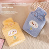 A light blue plush animal hot water bottle with a smiling face is shown next to a yellow plush animal hot water bottle.