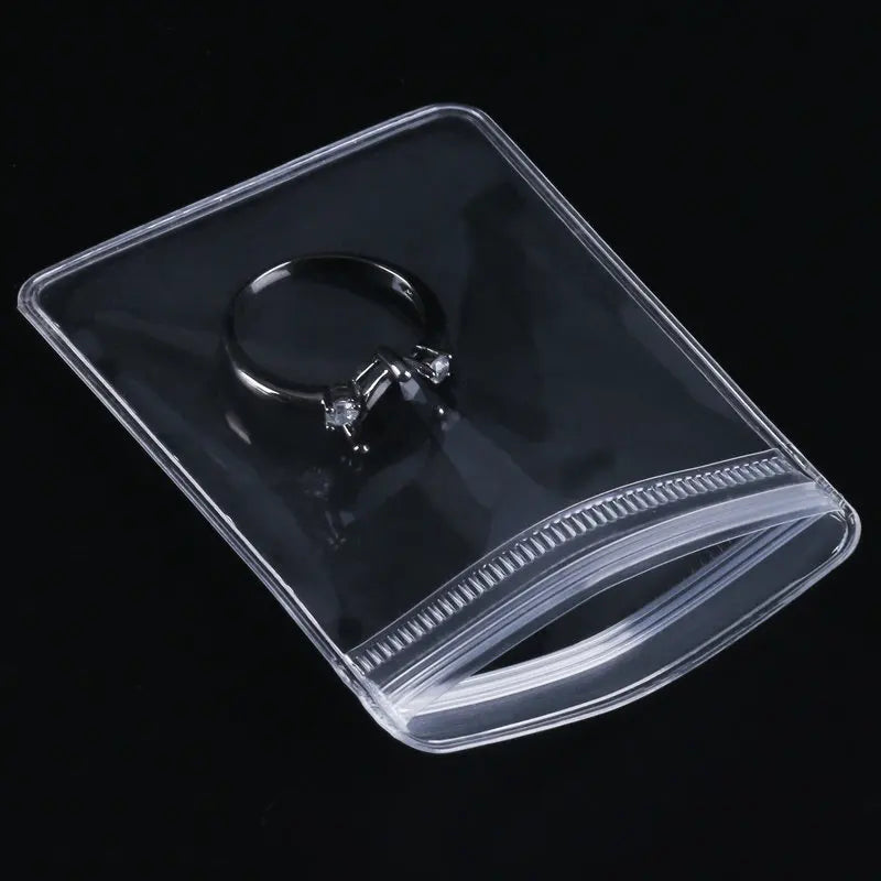 A clear PVC zip lock jewelry pouch containing a silver ring with a diamond setting.