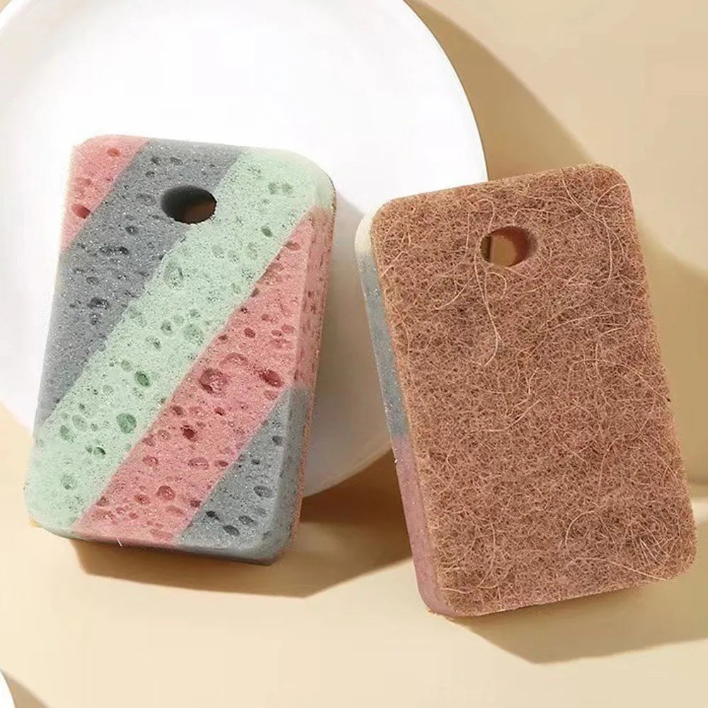 A set of two double-sided cleaning sponges, one gray and green striped, and one brown, resting on a light surface.