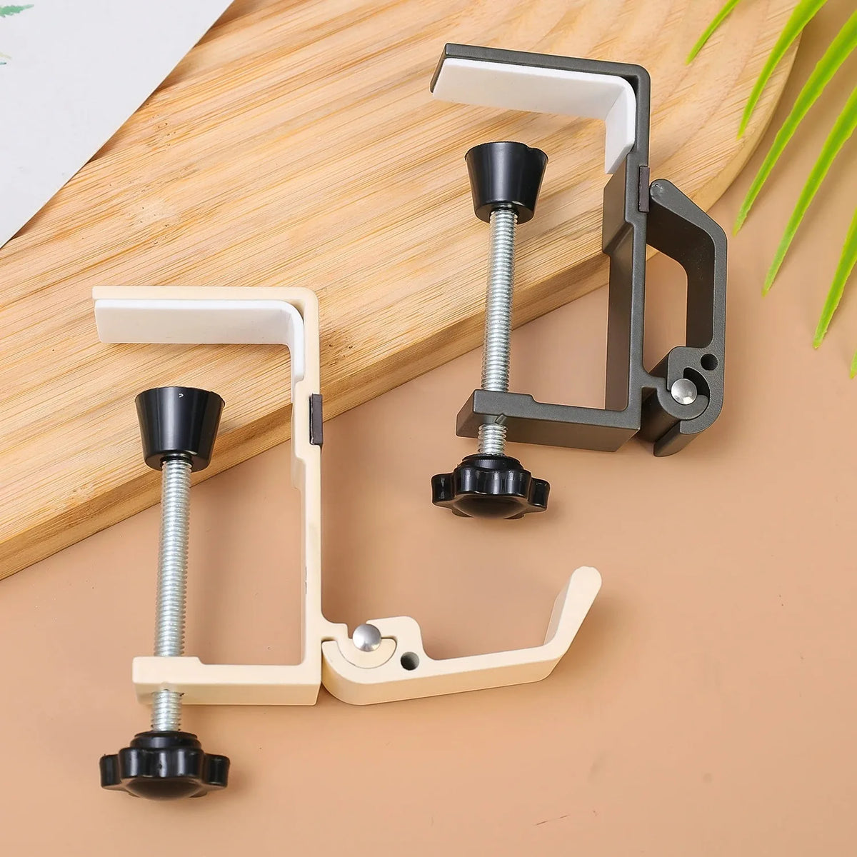 A set of adjustable desk hooks and hangers made of metal and plastic, shown on a wooden surface.