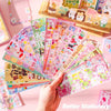 A hand holds a fan of colorful kawaii DIY sticker packs for crafting and decoration.