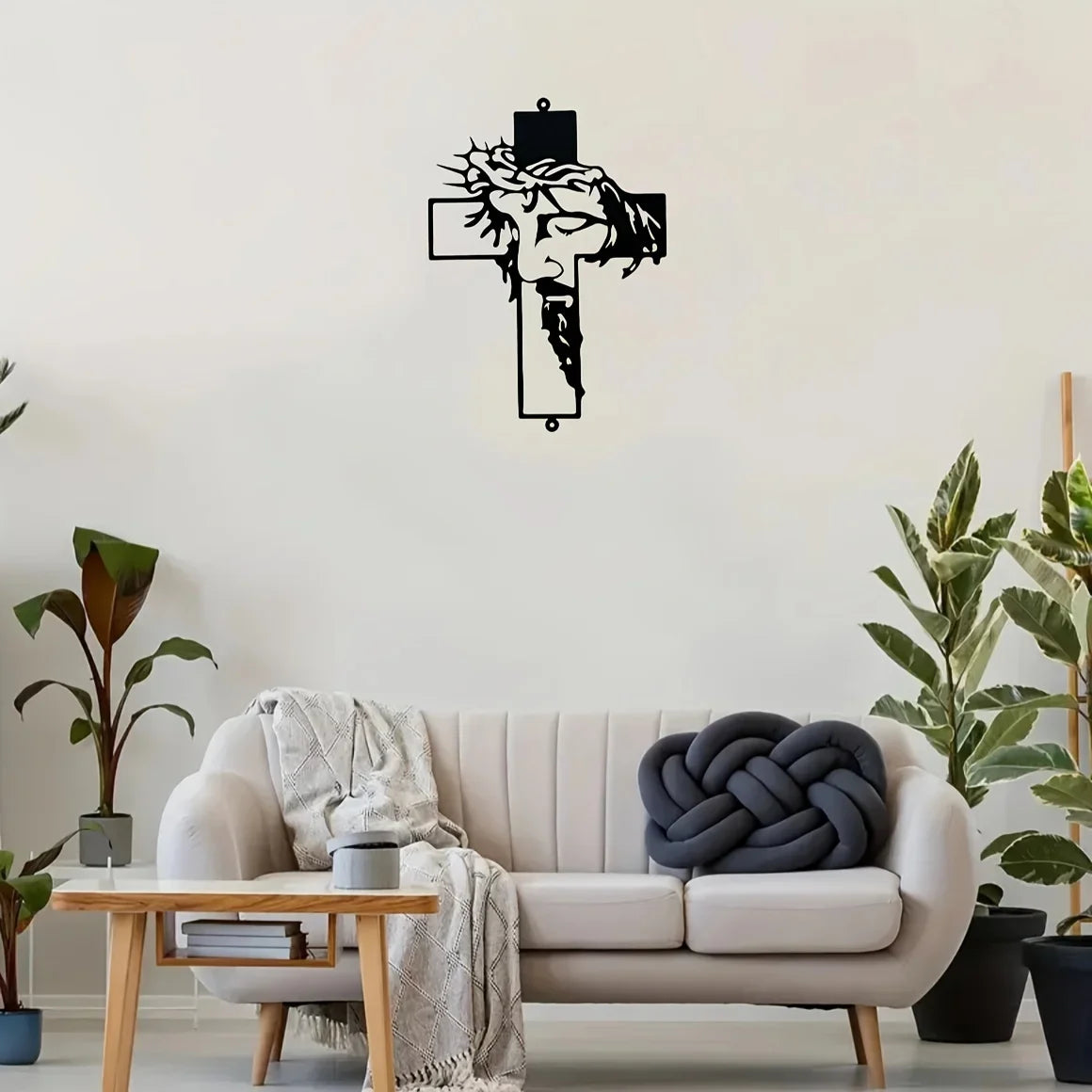 Black metal cross wall art decor hanging on a white wall above a light-colored sofa.