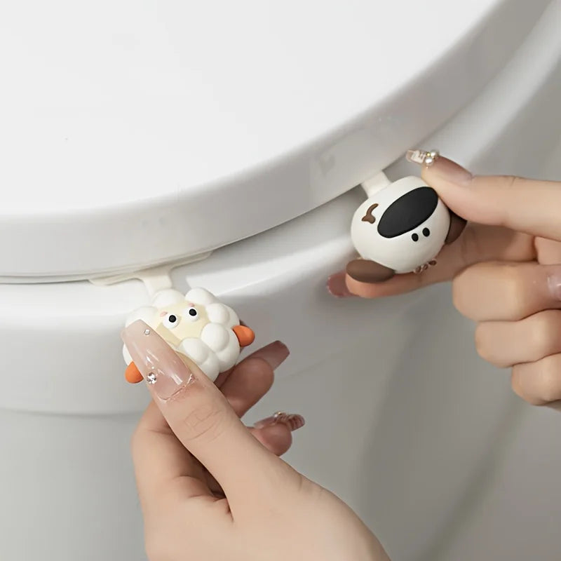 Hands are lifting a white cartoon toilet seat lifter handle out of the toilet bowl.