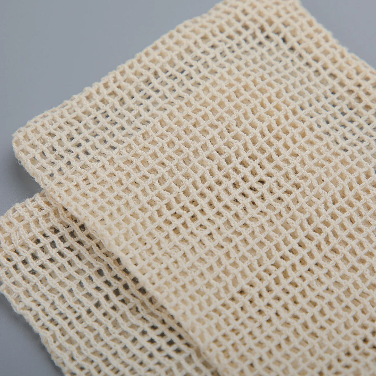 A set of natural beige cotton mesh soap saver pouches.