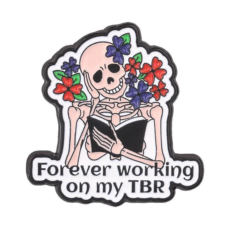 Insignia de esmalte con calavera sosteniendo un libro abierto rodeado de flores