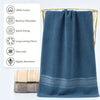 A dark blue ultra-absorbent pure cotton bath towel hanging next to rolled towels and features washing and drying icons.