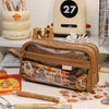 A brown transparent pencil pouch is shown next to various art supplies and a yellow box.