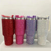 Cuatro vasos térmicos de strass apilados en tonos rojo, rosa, púrpura y plata con pajitas.