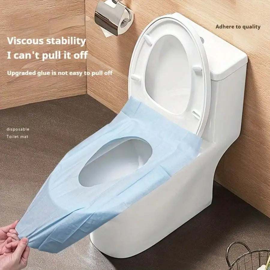 A disposable toilet seat liner is being placed on a white toilet bowl in a bathroom setting.