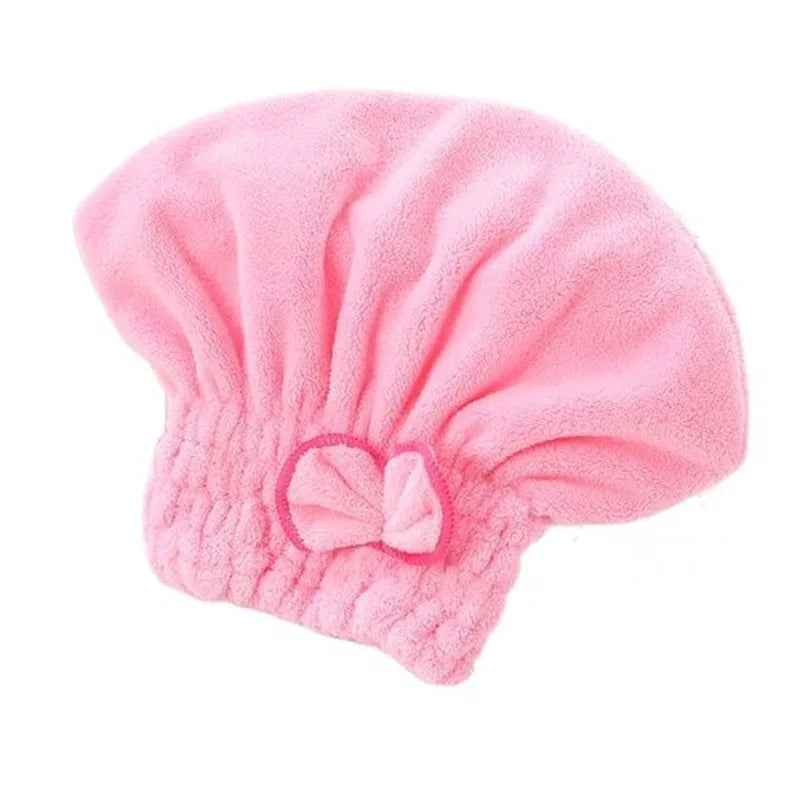 A pink microfiber hair drying towel cap with a bow detail.
