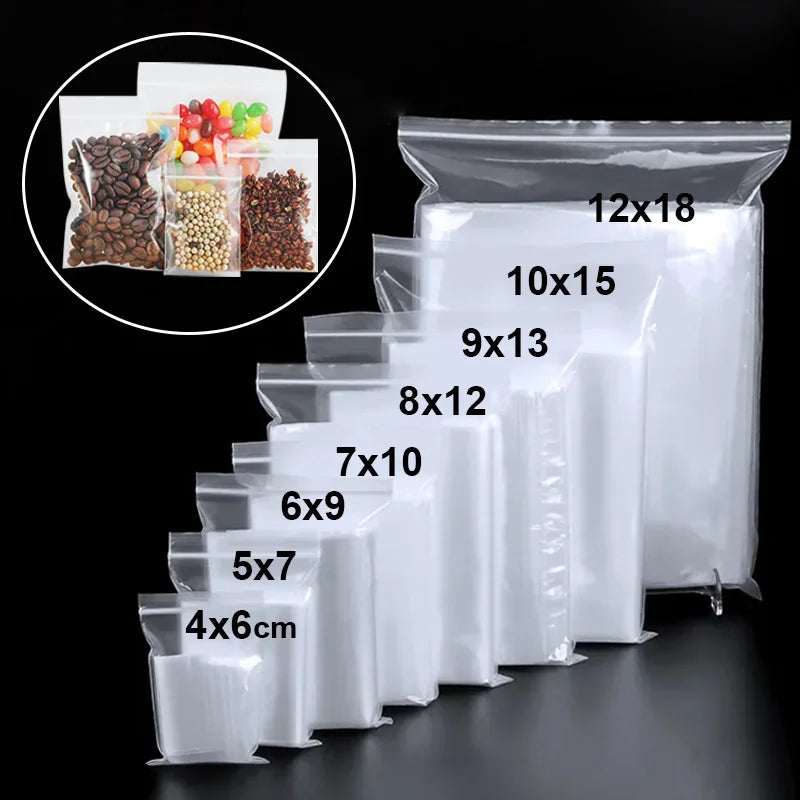 Una colección de bolsas reutilizables tipo ziplock transparentes de varios tamaños apiladas sobre una superficie oscura.