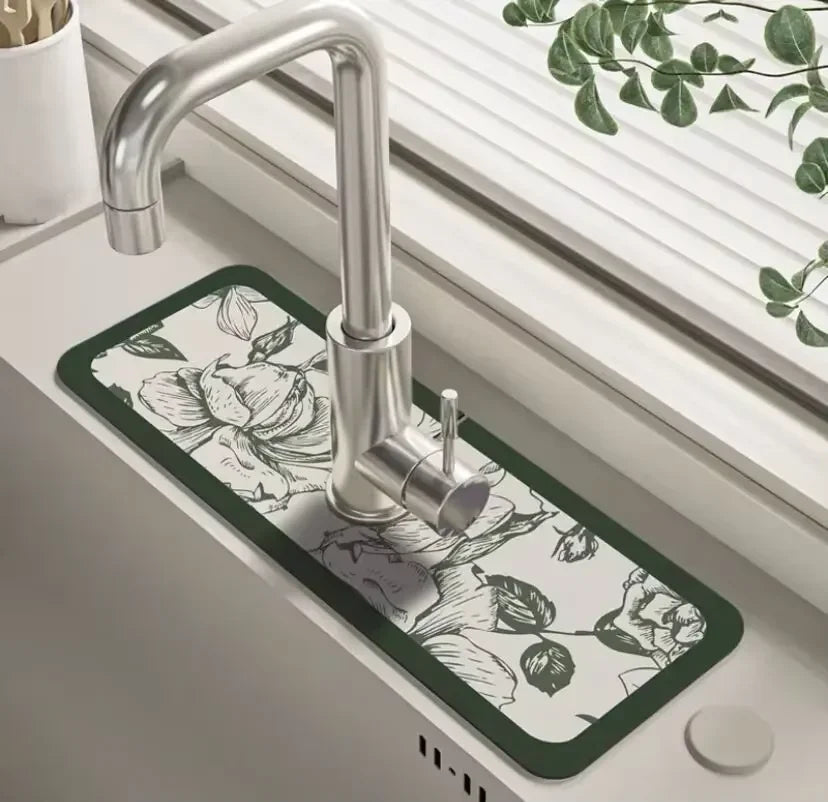 A modern chrome faucet mounted on a dark green mat in a kitchen sink.