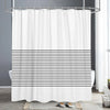 White shower curtain with horizontal black lines and a metal rod hanging in a bathroom setting.