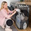 A woman is using a durable mesh laundry basket organizer for daily use next to a washing machine.