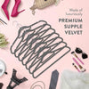 A set of premium velvet slim hangers displayed on a pink background with accessories.