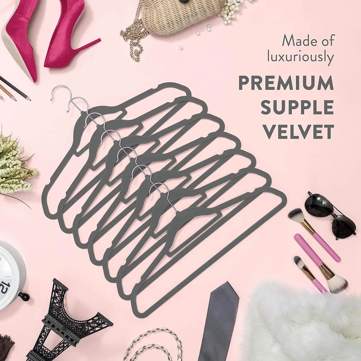 A set of premium velvet slim hangers displayed on a pink background with accessories.