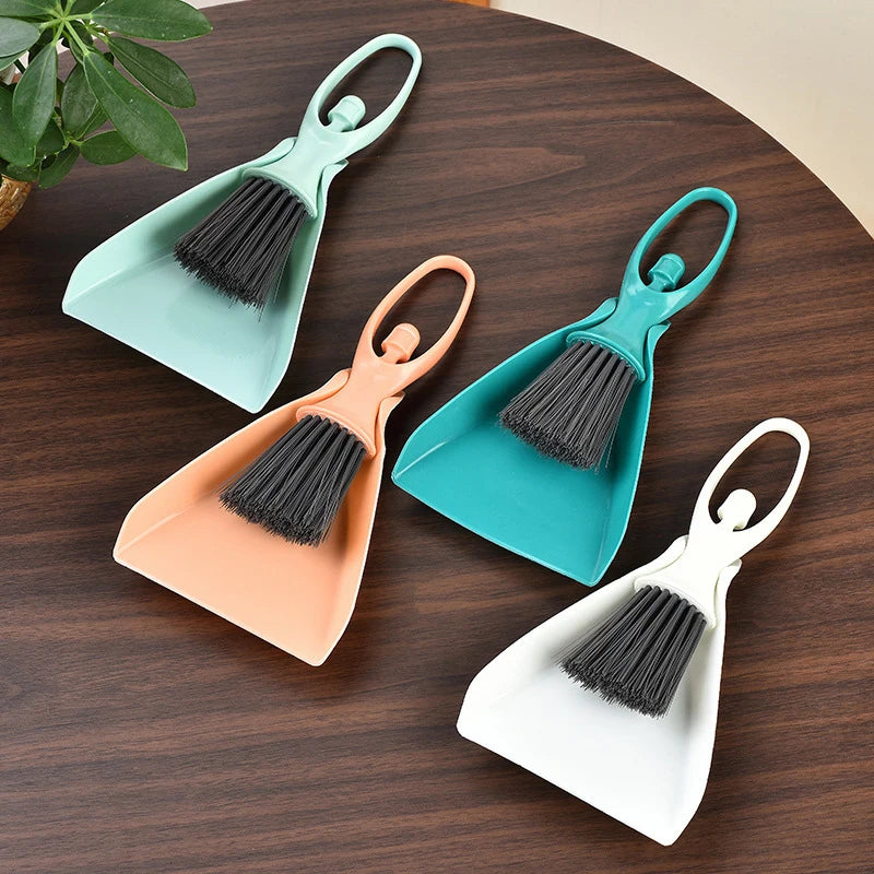 A set of three mini broom and dustpan tools in teal, peach, and white for cleaning desks and keyboards.