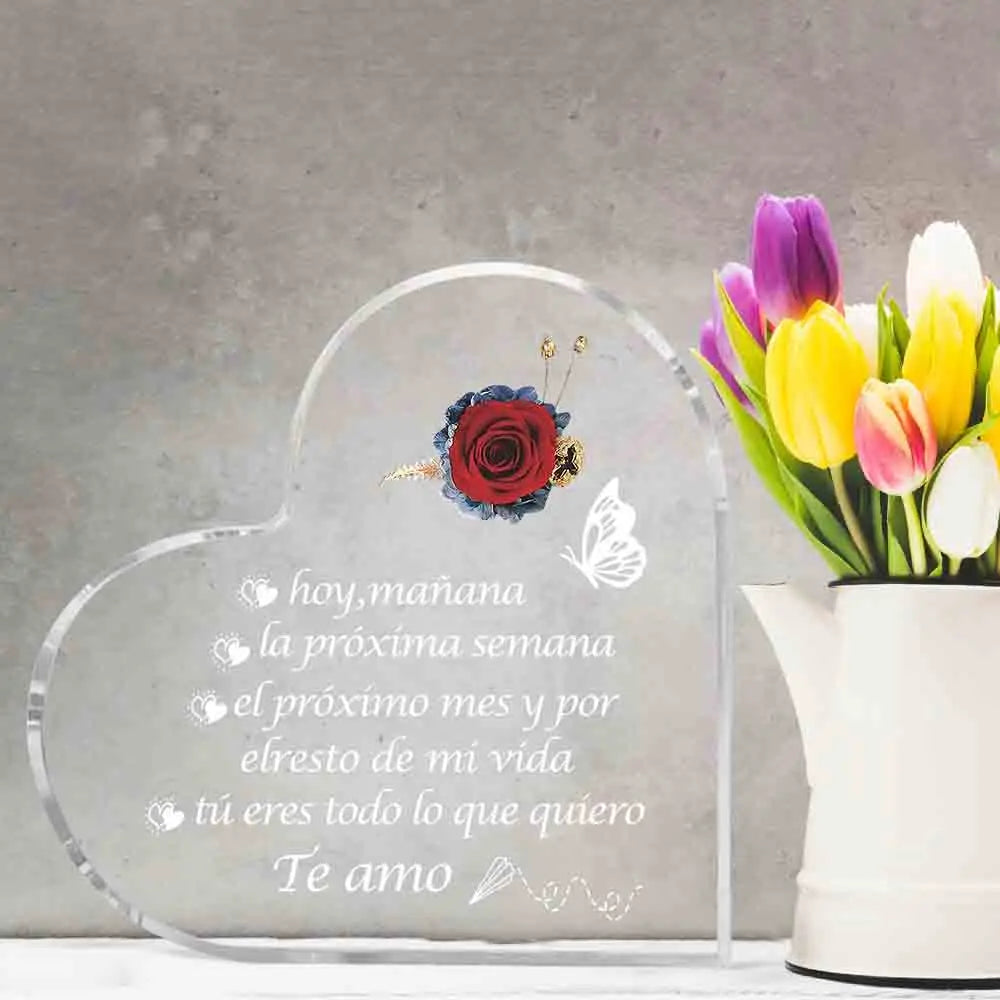 Placa de acrílico con forma de corazón grabada en texto en español sobre el amor y un ramo de tulipanes.