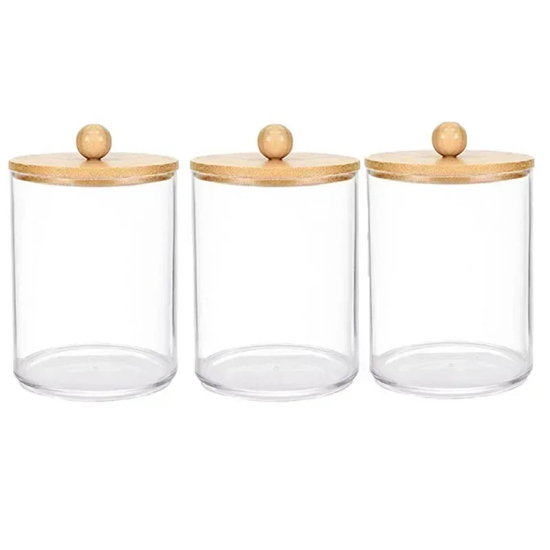 Three clear glass apothecary jars with wooden lids and cork stoppers for storage organization