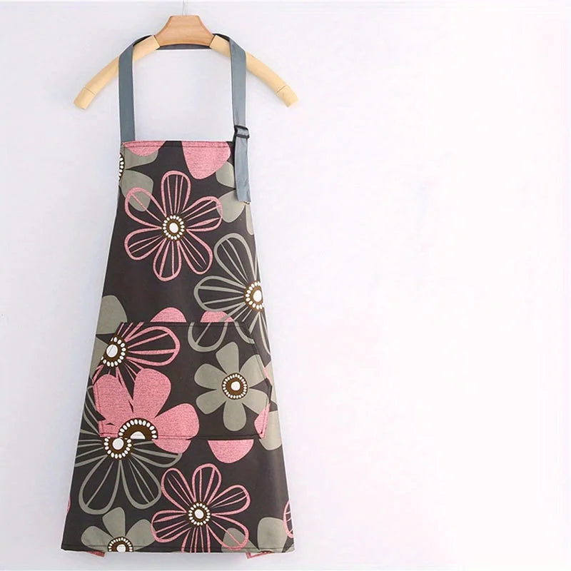 A dark apron with a floral print featuring pink and gray flowers is hanging on a wooden hanger.
