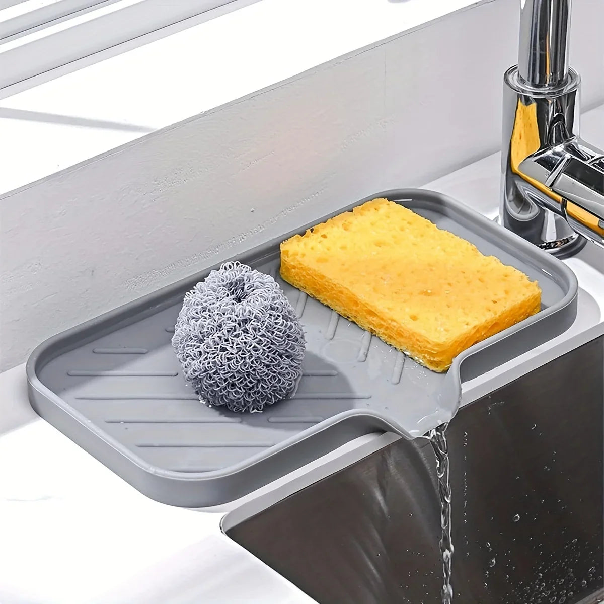 Silikon-Abwaschschale hält eine gelbe Schwamm und Reinigungswerkzeuge, die in einer Küchenspüle gewaschen werden.