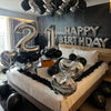 Silver and black balloons spelling out Happy Birthday with a number 2 and 1 decoration