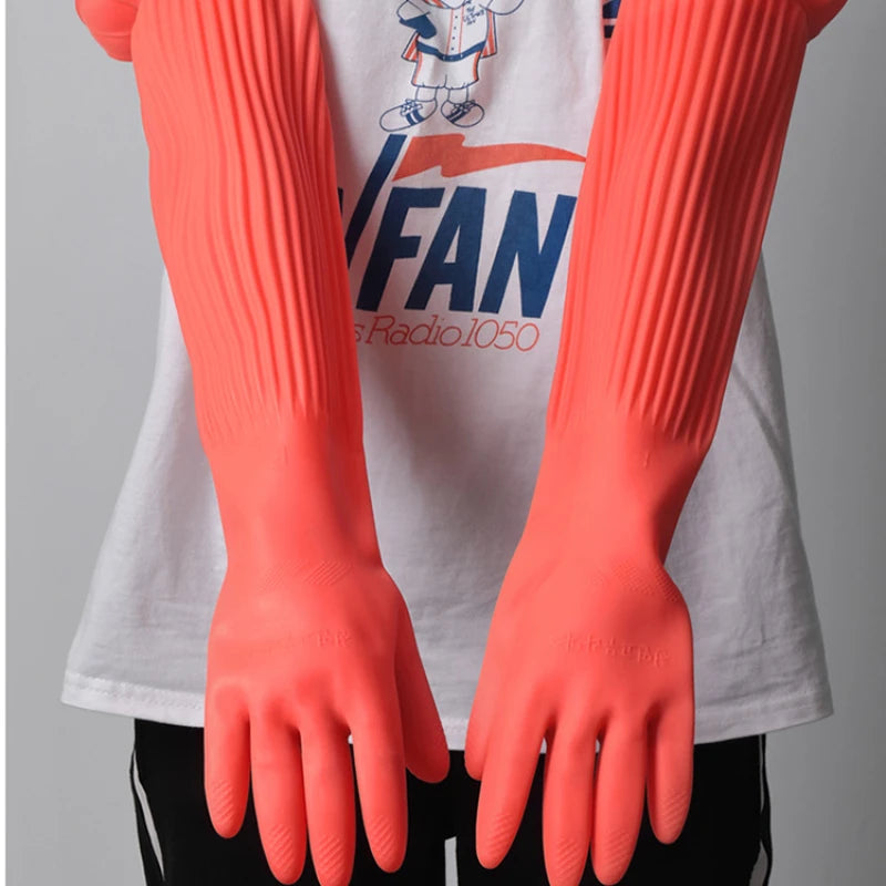 A pair of bright orange silicone dishwashing gloves worn on the hands against a white shirt.
