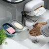 A hand is placing a white bar of soap into a gray dish on a white countertop next to a modern faucet.