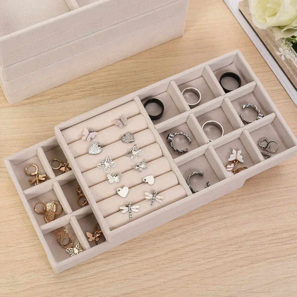 A light beige velvet jewelry organizer tray filled with various rings and earrings.