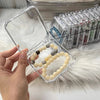 A hand holds a clear plastic jewelry organizer box filled with light yellow and gray beads, next to a clear plastic storage t