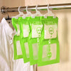Green hanging bags filled with moisture absorbers are displayed on a metal rod in a wardrobe.