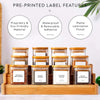 A set of five pre-printed glass spice jars with bamboo lids displayed in a wooden tray.