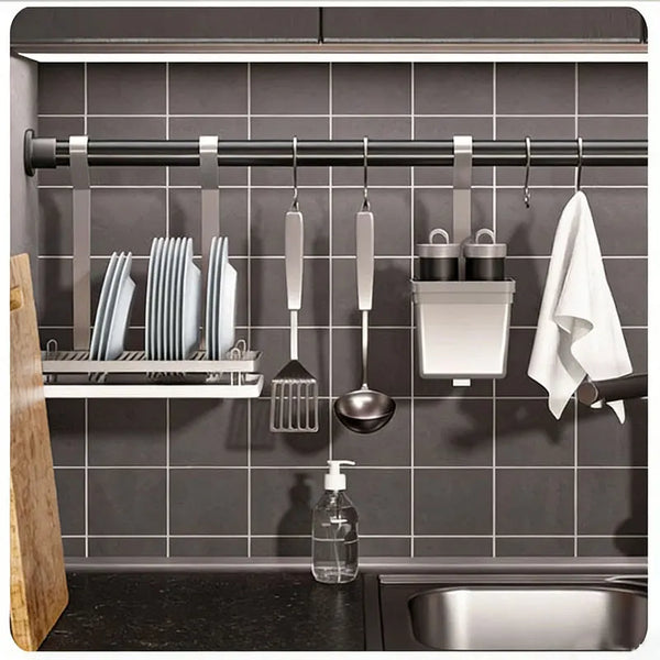 A stainless steel spring tension shower curtain rod mounted in a kitchen cabinet, holding various kitchen utensils and a whit