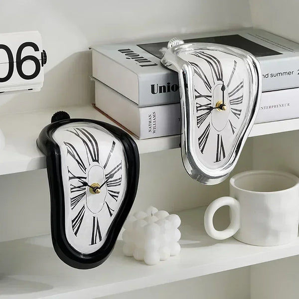 A silver melting wall clock with a Dali style design displayed on a white shelf.