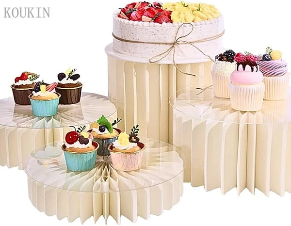 A tiered cake display featuring pink and white frosting and fresh fruit on a round pedestal stand.