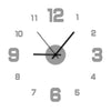 A close-up view of a round analog clock face with gray numbers and black hands.