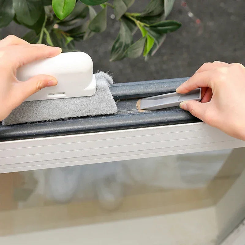 Hands are cleaning a groove and track with a white brush on a gray cleaning tool.