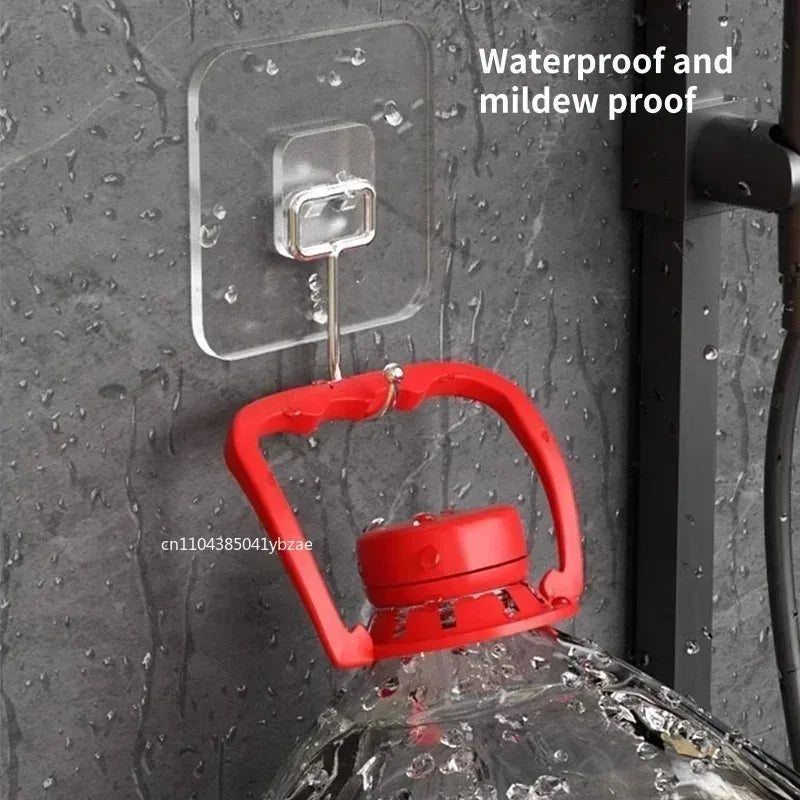A red rotating wall hook is attached to a clear adhesive mount on a gray textured wall.