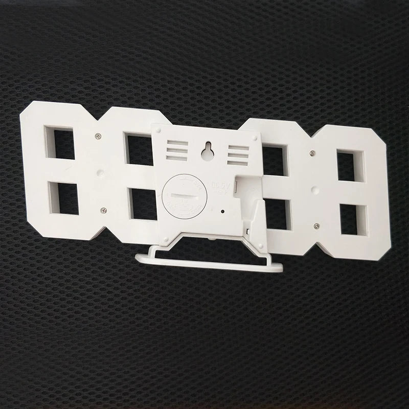 Weiße 3D-LED-digitale Wanduhr mit USB-Ladeanschluss und Montagehalterung.