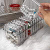 A hand is holding a clear plastic jewelry organizer box filled with various beads and jewelry.