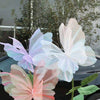 A cluster of pink, purple, and white 3D simulated butterfly decorations on a green plant stem.
