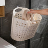 A white folding hand-held clothes storage basket is shown hanging on a glass shower door with a towel inside.