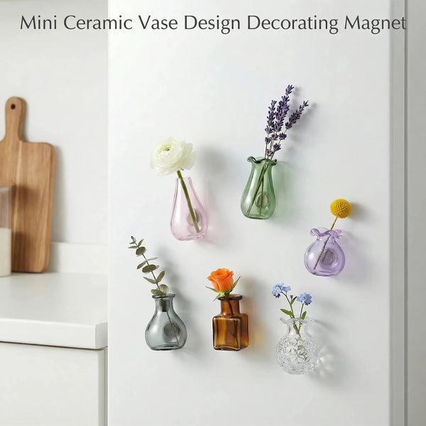 A collection of decorative glass flower vases and a magnetic design decorating magnet displayed on a white surface.