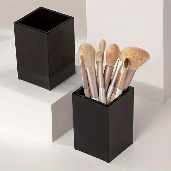 A black acrylic organizer box holds several cosmetic makeup brushes.