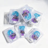 A collection of clear plastic containers filled with blue and purple candles for a birthday celebration.